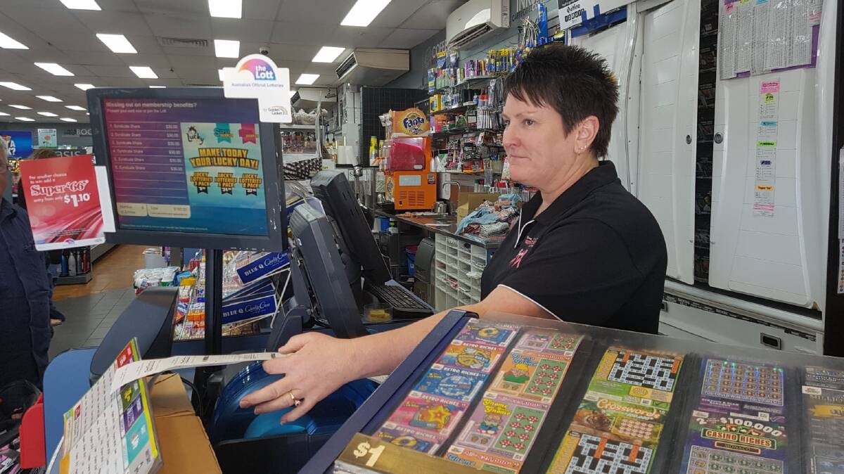 WINNING TICKETS: Shop assistant Susan Ward hands a customer her Lotto tickets for Thursday night. Photo: Melissa North