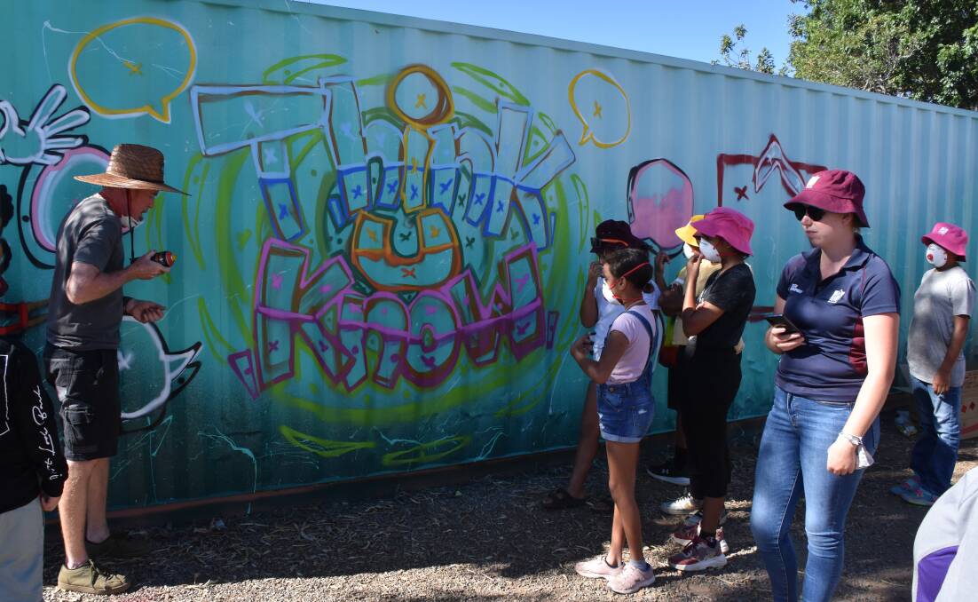 Wally (left) teaches local children techniques of graffiti art. Photo: Samantha Campbell.