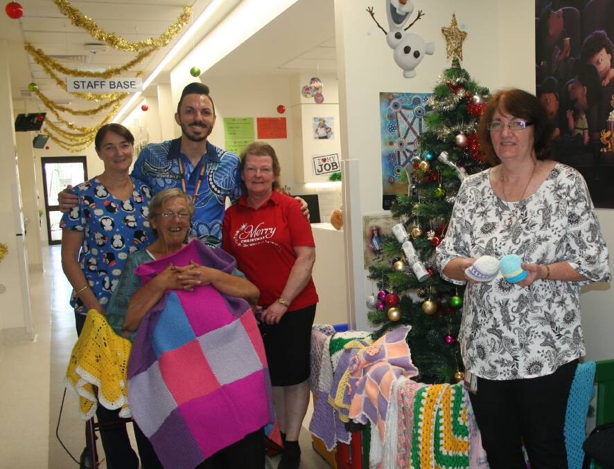 Paediatric nurses Sue Maye and Nathan Parrish with Brigitte Sharp and Lorraine Howard from the Colonial Markets, with Nurse Unit Manager, Susan Ryan, with some of the tiny baby beanies donated.