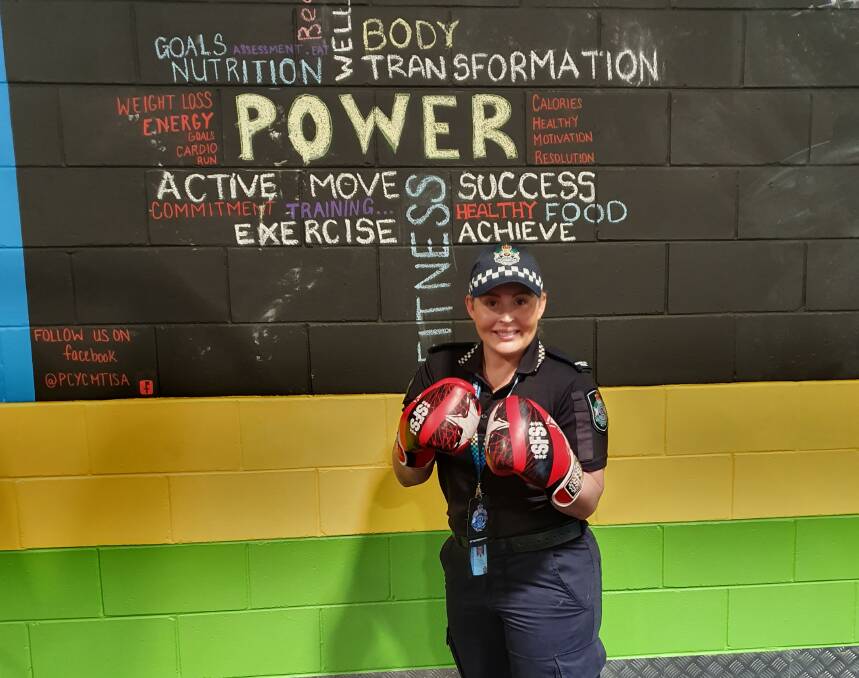 Senior constable Aimee Sewell standing in front of the PCYC motivation wall. Photo: Supplied. 