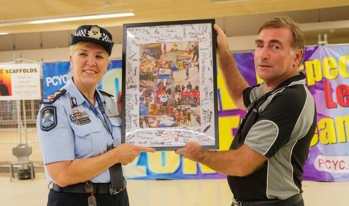 Katarina Carroll presents Youth Zone building owner Simon Pate with a signed photo from the youth for providing six months of free rent. Photo: ABC North West Queensland