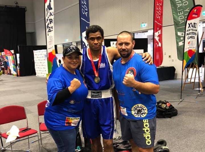 GOLD: Mount Isa's Sunny Raitava takes wins his huge bout in Adelaide with coaches James and Kerry Derrick. 