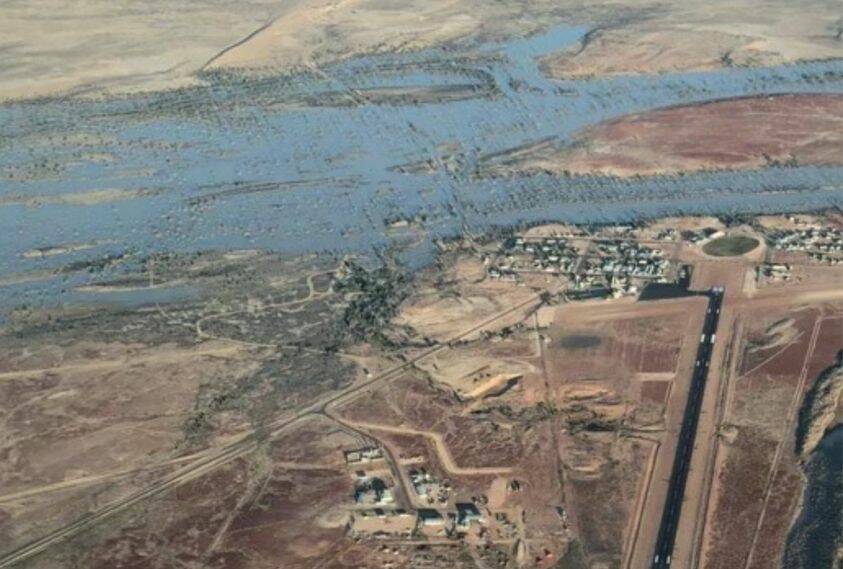 An aerial shot shows the Diamantina cutting off Birdsville township from the road south to the racetrack (top of the image).