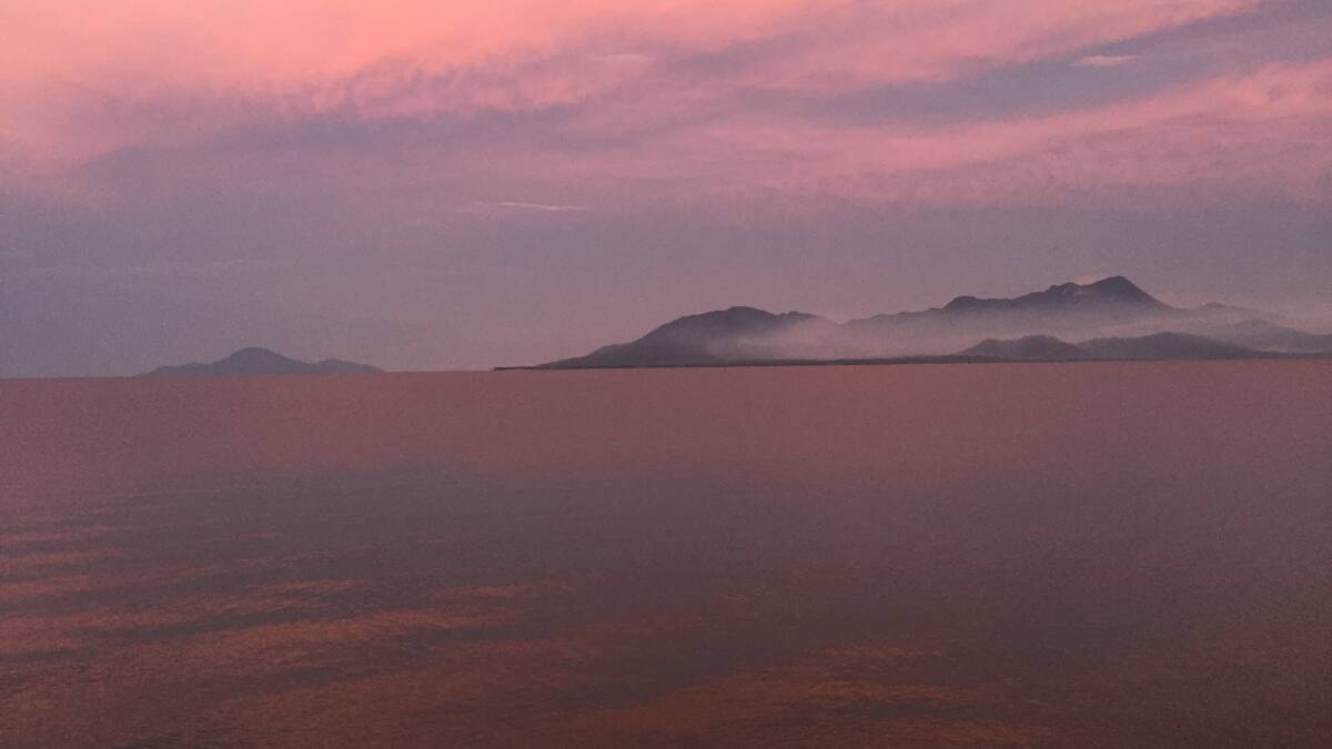 AFTERMATH: The sea and sky around Hinchinbrook Island glow an extraordinary shade after the fires last week as seen from Cardwell. Photo: Derek Barry
