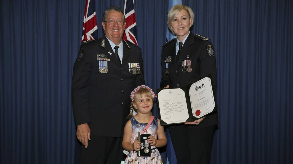 Renee Hanrahan with her daughter Mila Hanrahan, aged 5, receiving her medal and clasp from Commissioner Ian Stewart.