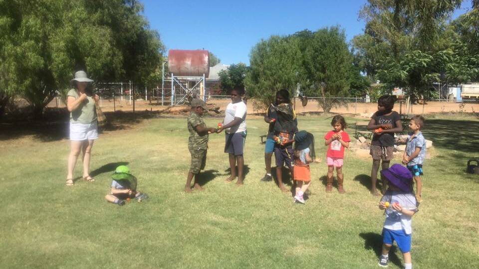 TREATS: Urangandi children enjoy an Easter egg hunt after the army visitors hid the eggs. Photo: supplied.