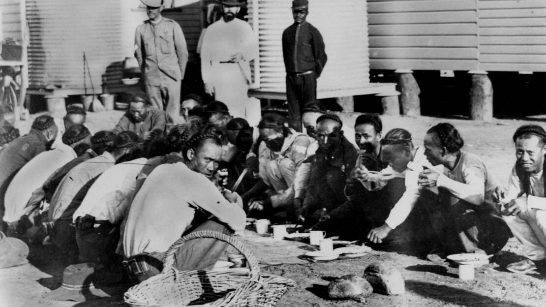 Chinese prisoners fed under supervision in the Jail Yard, Burketown ca. October 1900. These Chinese workers were arrested crossing the Northern Territory/Queensland border without permission. They were arraigned to Normanton for trial. There were 25 people in total. (Original photograph one of four featured in the Queenslander, 27 October 1900, p. 876). Negative number 44909, John Oxley Library, State Library of Queensland. 