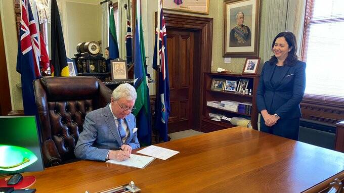 The Premier watches as the Governor of Queensland signs the writs yesterday before she flew to Mount Isa.