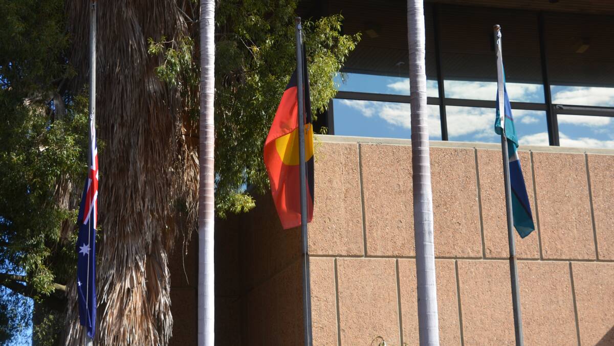 Aboriginal, Australian and Torres Strait Islander flags fly at the Mount Isa Naidoc Week flag raising on Sunday.