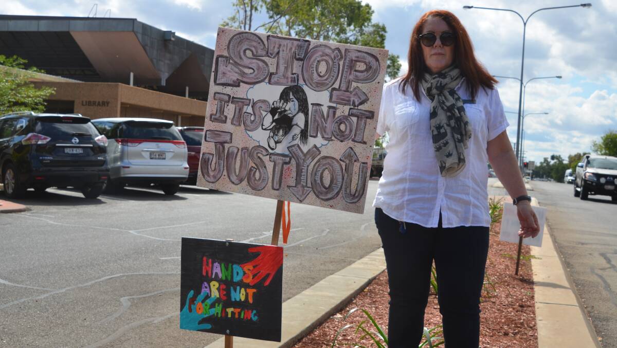 POWERFUL MESSAGE: Leeanne Harris of Centacare with a sign near the library that reads "Stop. It's Not Just You" Photo: Derek Barry