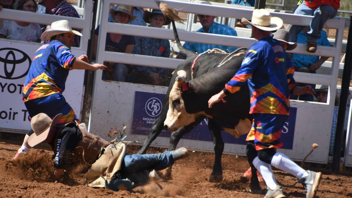 Darryl Chong (left) comes to the aid of yet another bull rider in the Mount Isa Rodeo. Photo: Derek Barry