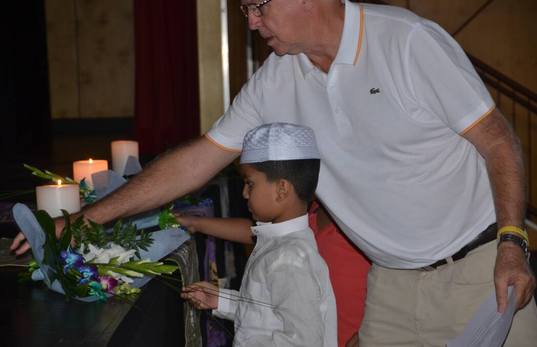 Fr Mick helps a young boy place a candle at Mount Isa's service for Christchurch on Friday.