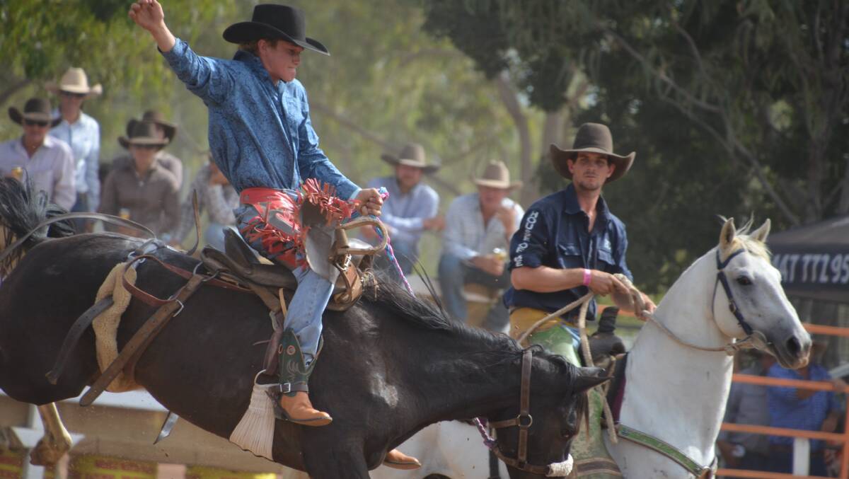 A pick-up man watches on as a competitor has a ride in the 2017 Normanton Rodeo.