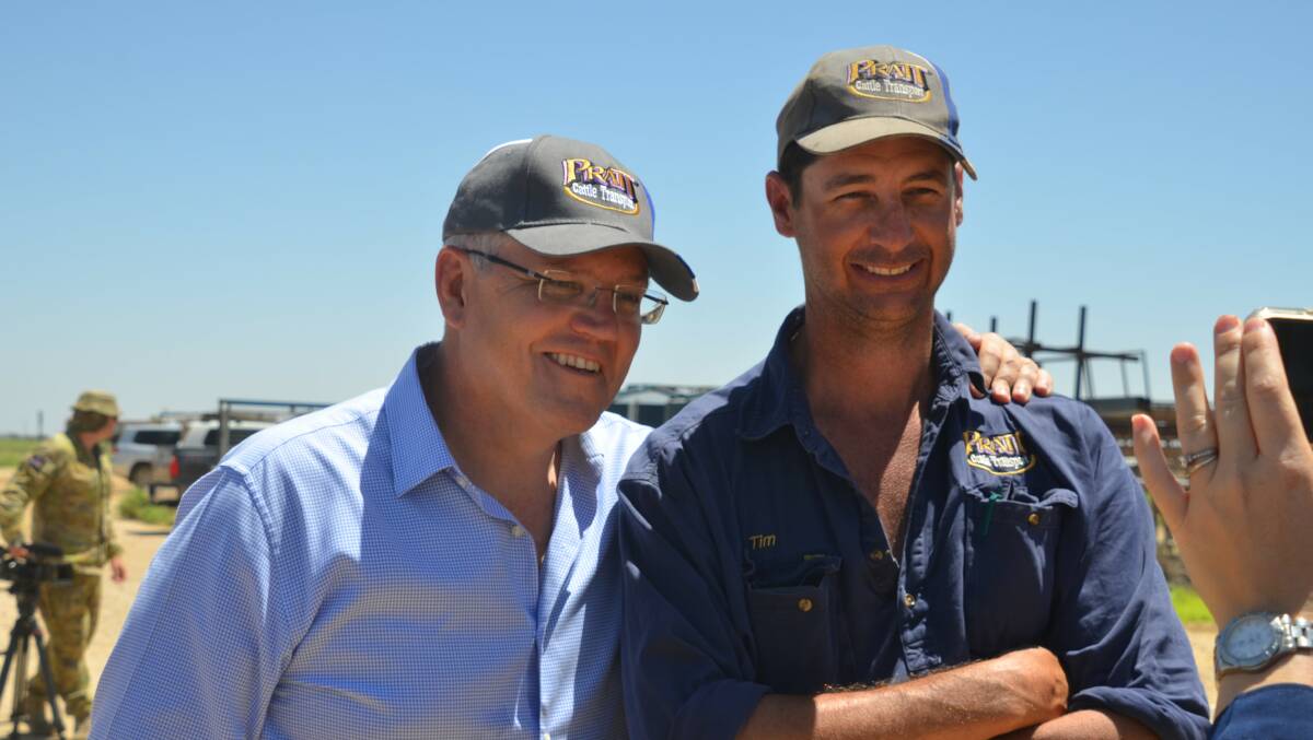 IF THE CAP FITS: Prime Minister Scott Morrison and businessman Tim Pratt proudly wear Pratt Cattle Transport caps in Julia Creek. Photo: Derek Barry