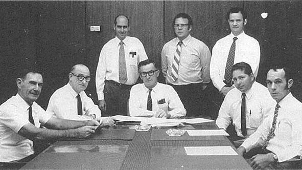 Cliff Jury (centre) leads a meeting of 1971 credit union directors (L-R) Joe Doherty, Gerald Behan, John Wilmot, Jim O'Toole, Nev Nicholls, Geoff Topfer, and Bill Harper.