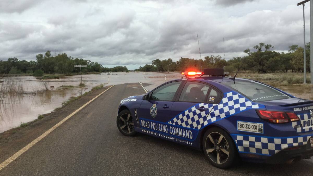 Police patrol the closed Flinders Hwy at Canal Creek west of Cloncurry in a previous wet season.