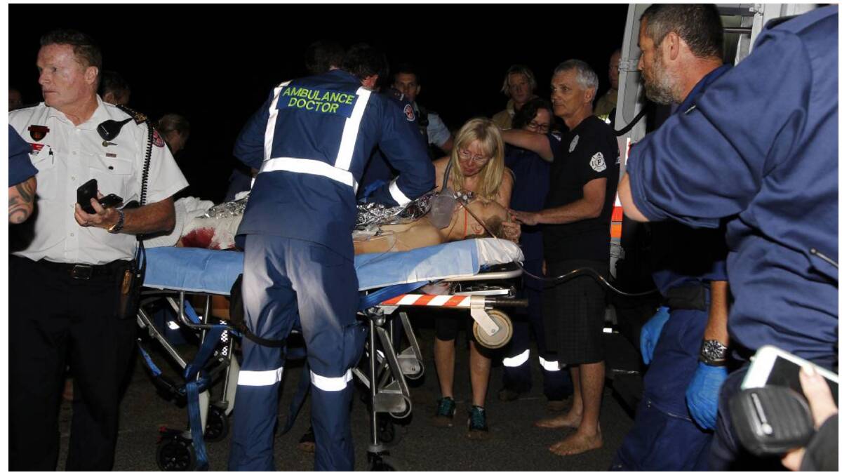 Connellan's parents Mal and Gail at their son's side on March 30, 2016 as crew from an ambulance rescue helicopter tend to his injuries at Bombo Beach. Picture: Sylvia Liber 