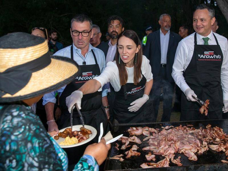 NZ Prime Minister Jacinda Ardern (c) has served up Waitangi Day breakfast at Te Whare Runanga.