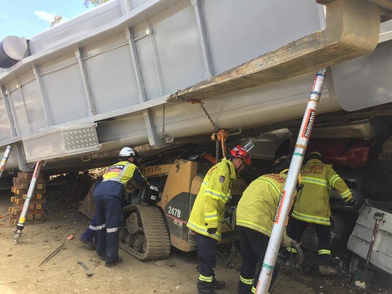 A man has been trapped in a bobcat after it was crushed under a truck at a wrecking yard in Sydney.