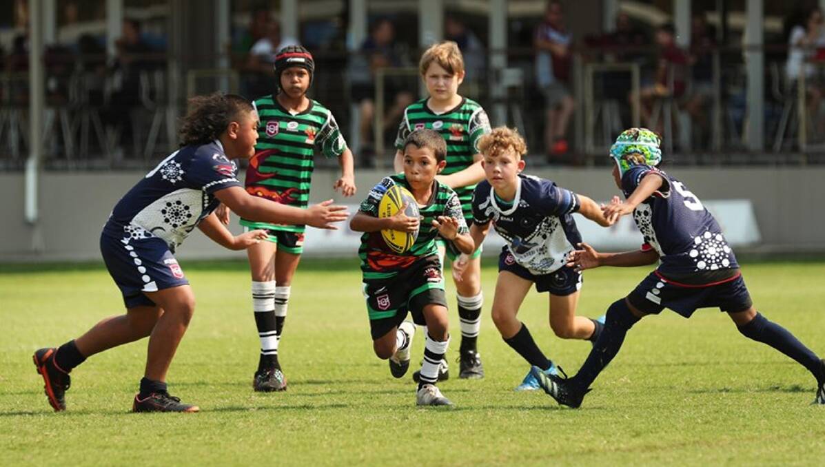 Ezra Cedric runs the ball between Andrew Keeman (right) and Miesha Rapson (left) during the Townsville competition. 