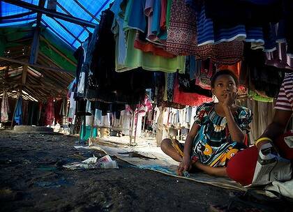 A young woman helps her mother selling second hand clothes at the Waigani market.